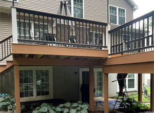 General Contractor is a custom deck builder in Pittsburgh constructing a spacious wooden deck with railings in a suburban backyard.